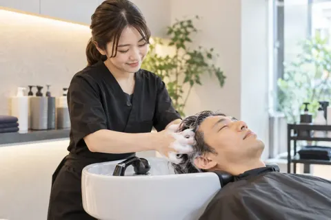 シャンプー台でお客様の髪を洗うスタッフ（育毛・発毛・薄毛ケアの写真 No.28）
