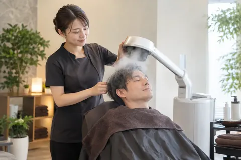 頭にスチームを当てる機械を使うスタッフ（育毛・発毛・薄毛ケアの写真 No.31）