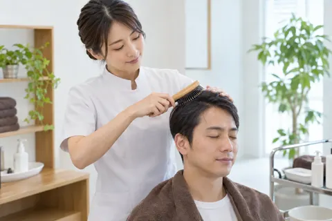 ブラシで頭皮をとかすスタッフ（育毛・発毛・薄毛ケアの写真 No.33）