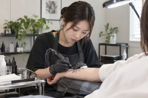 お客様の腕に機械で線を入れる施術者（タトゥー・アートメイクの写真 No.39）