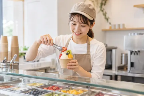 カップのアイスにくだものをのせる店員（アイス・クレープ・かき氷の写真 No.22）