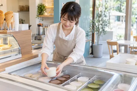 冷凍ケースにアイスの容器を補充する店員（アイス・クレープ・かき氷の写真 No.24）