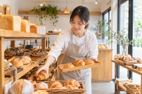 パンの棚に焼きたてのパンを補充する店員（パン・ベーカリーの写真 No.28）