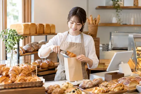 パン屋のレジでパンを袋に入れる店員（パン・ベーカリーの写真 No.29）