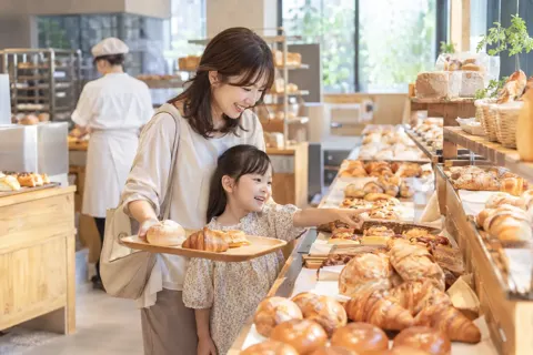 子どもと一緒にトレーでパンを選ぶ親（パン・ベーカリーの写真 No.37）