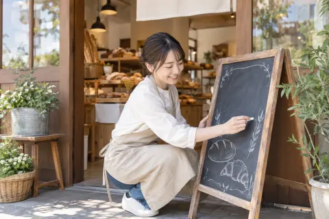 店の前の黒板に今日のパンを書く店員（パン・ベーカリーの写真 No.46）