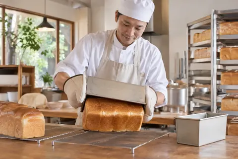 焼きたての食パンを型から出す職人（パン・ベーカリーの写真 No.47）