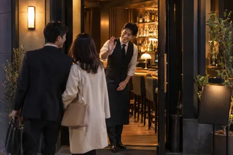帰るお客様を店の入口で見送るバーテンダー（バー・ショットバーの写真 No.43）