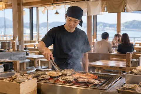 炭火の具合を見に来る店員（浜焼きの写真 No.22）