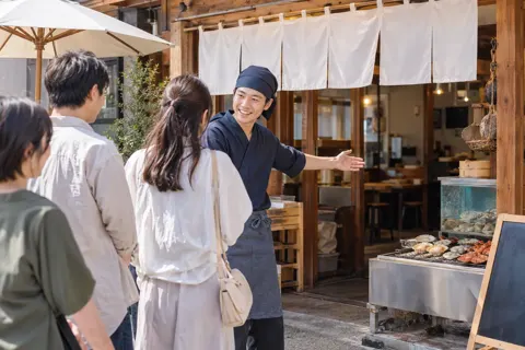 店の前で並ぶお客様に声をかける海鮮の店の店員（海鮮丼・浜焼きの写真 No.26）