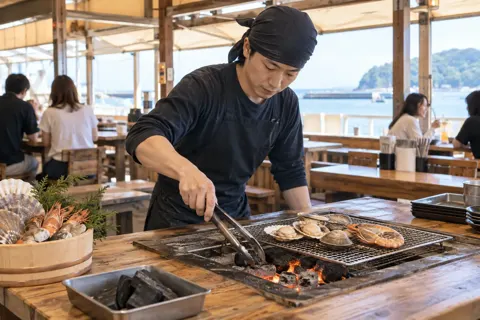網の下の炭を足して火を整える店員（海鮮丼・浜焼きの写真 No.30）