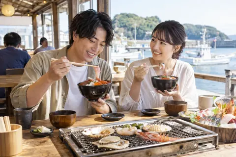 港を見ながら海鮮丼を食べる二人（海鮮丼・浜焼きの写真 No.31）