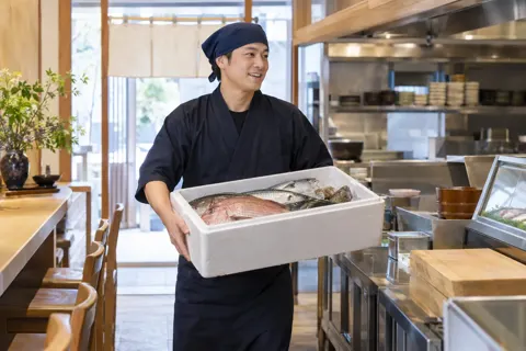 魚の入った発泡の箱を運びこむ店員（海鮮丼の写真 No.22）