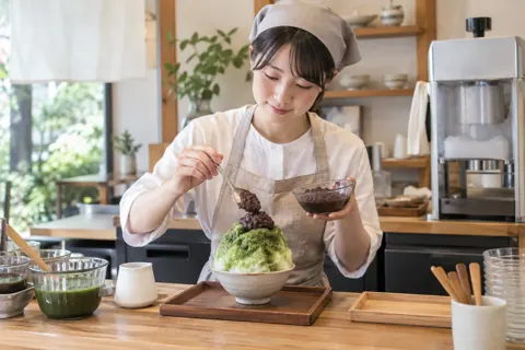 抹茶のかき氷にあんこをのせる店員（かき氷の写真 No.23）
