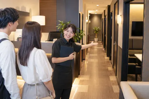 受付でお客様に部屋を案内するカラオケの店員（カラオケ・カラオケボックスの写真 No.25）