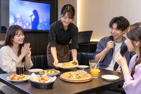 カラオケの部屋のテーブルに料理を置く店員（カラオケ・カラオケボックスの写真 No.29）