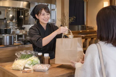 持ち帰りのもつ鍋セットを渡す店員（もつ鍋の写真 No.21）