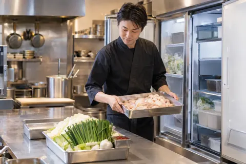 もつ鍋の具材を冷蔵庫から出す料理人（もつ鍋の写真 No.23）