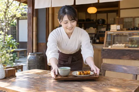店先で団子と一緒にお茶を出す店員（和菓子・団子・せんべいの写真 No.32）