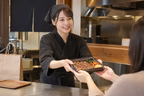 持ち帰りの焼肉弁当を渡す店員（焼肉の写真 No.22）