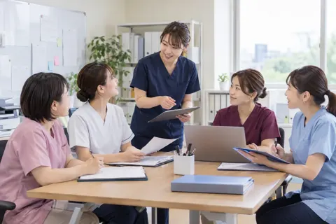 事務所で朝の申し送りをする看護師たち（訪問看護・訪問診療の写真 No.21）