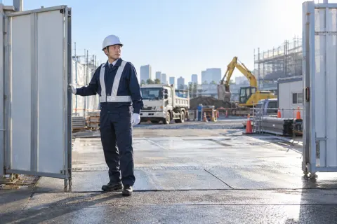 建設現場の朝に門を開ける警備員（警備・セキュリティの写真 No.50）