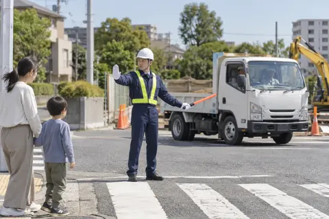 横断歩道で歩行者を止めて工事の車を通す警備員（警備・セキュリティの写真 No.51）