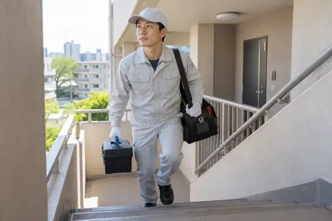 道具を持って集合住宅の階段を上るスタッフ（水漏れ・水道修理（緊急）の写真 No.58）