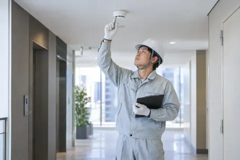 ビルの火災報知器を点検する作業員（電気工事・空調・電気設備の写真 No.51）