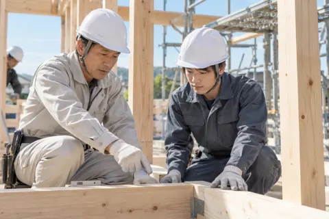 ヘルメットをかぶった新人に教える先輩の職人（建築・建設その他の写真 No.43）