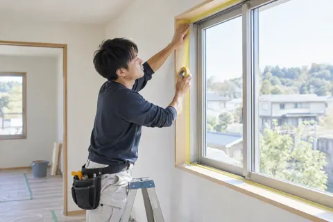 窓のまわりにマスキングテープをはる職人（内装・クロス・大工の写真 No.42）