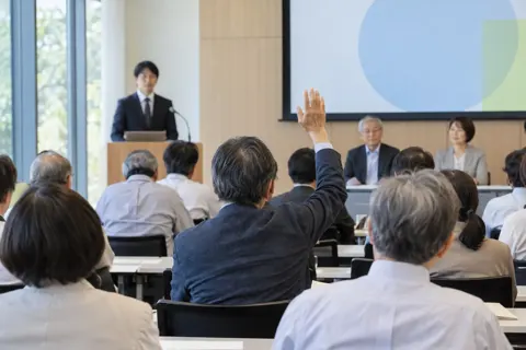 総会の会場で手を挙げて質問する会員（行政・公共・団体・組合の写真 No.18）