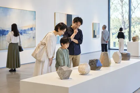 陶芸の作品が並ぶ展示台を見る来館者（美術館・ギャラリー・展示の写真 No.44）
