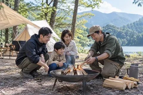 たき火のつけ方を教えるスタッフと親子（キャンプ場・グランピングの写真 No.22）