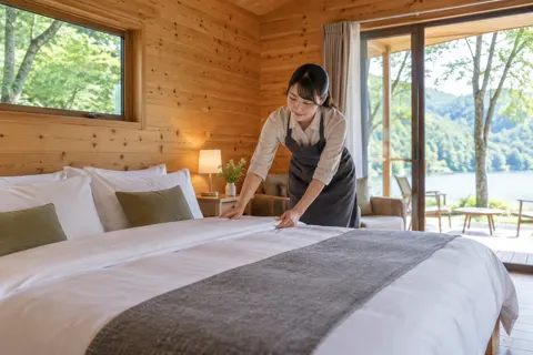 コテージのベッドを整えるスタッフ（キャンプ場・グランピングの写真 No.35）