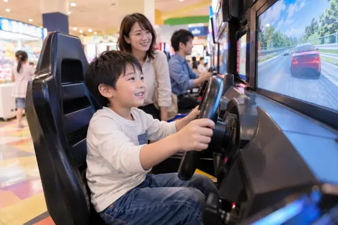 レースのゲームでハンドルをにぎる子ども（ゲームセンター・ボウリング・ビリヤードの写真 No.24）