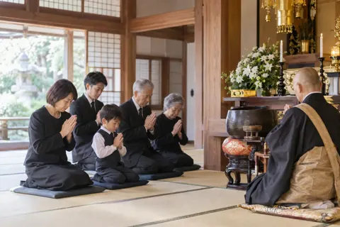 法事で手を合わせる家族とお坊さん（神社・寺院・教会の写真 No.37）