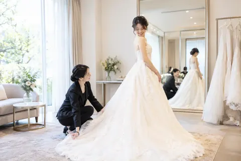 ドレスを試着する新婦とスタッフ（結婚式場・ウェディングの写真 No.27）