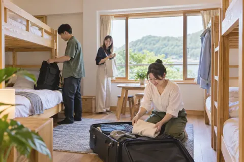 二段ベッドの部屋で荷物を整理するお客様（民泊・ゲストハウスの写真 No.20）