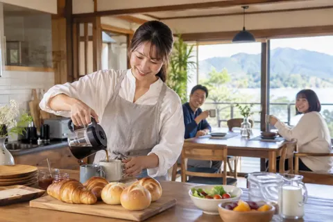 朝食のパンとコーヒーを用意するオーナー（民泊・ゲストハウスの写真 No.34）