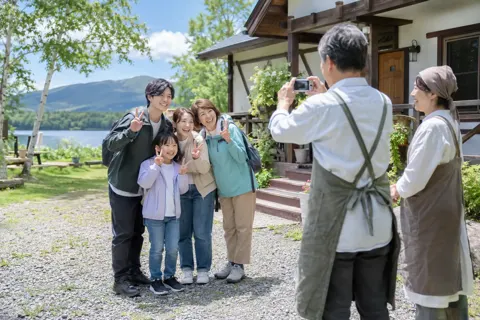 お客様と記念の写真を撮るオーナーの夫婦（ペンション・コテージの写真 No.32）
