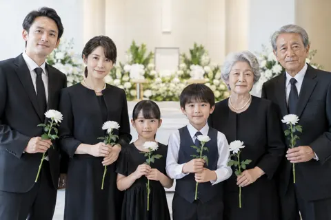 白い花を手に持ってならぶご家族（葬儀・葬祭・斎場の写真 No.35）