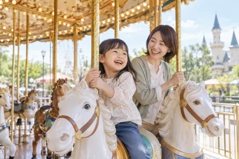 メリーゴーラウンドに乗る親子（水族館・動物園・テーマパークの写真 No.26）