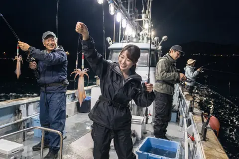 夜の船で明かりをつけてイカを釣るお客様たち（釣り船・遊漁船の写真 No.35）