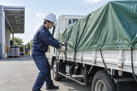 荷台にシートをかけてロープでしばるドライバー（運送・配送・トラックの写真 No.59）