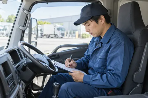 運転席で日報を書くドライバー（運送・配送・トラックの写真 No.62）