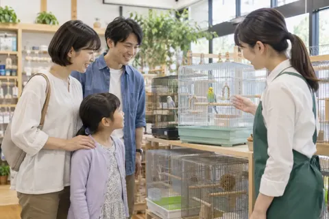 小鳥のかごを見る親子と店員（ペット用品店の写真 No.24）