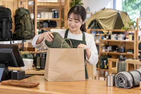 レジで品物をふくろに入れる店員（アウトドア・キャンプ用品の写真 No.19）