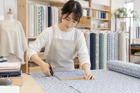 布を台の上で測って切る店員（文房具・手芸用品の写真 No.23）