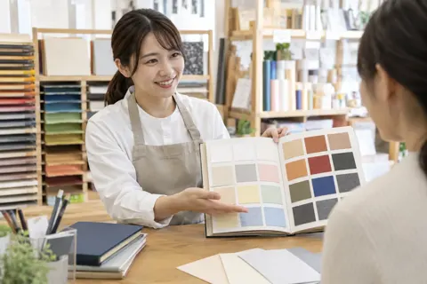 紙の見本帳を開いて見せる店員（文房具・手芸用品の写真 No.34）